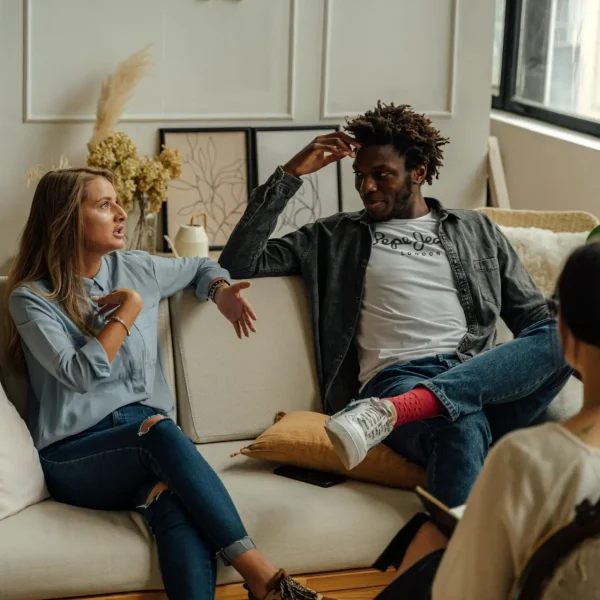 A couple is engaged in a lively conversation during a therapy session with a counselor.